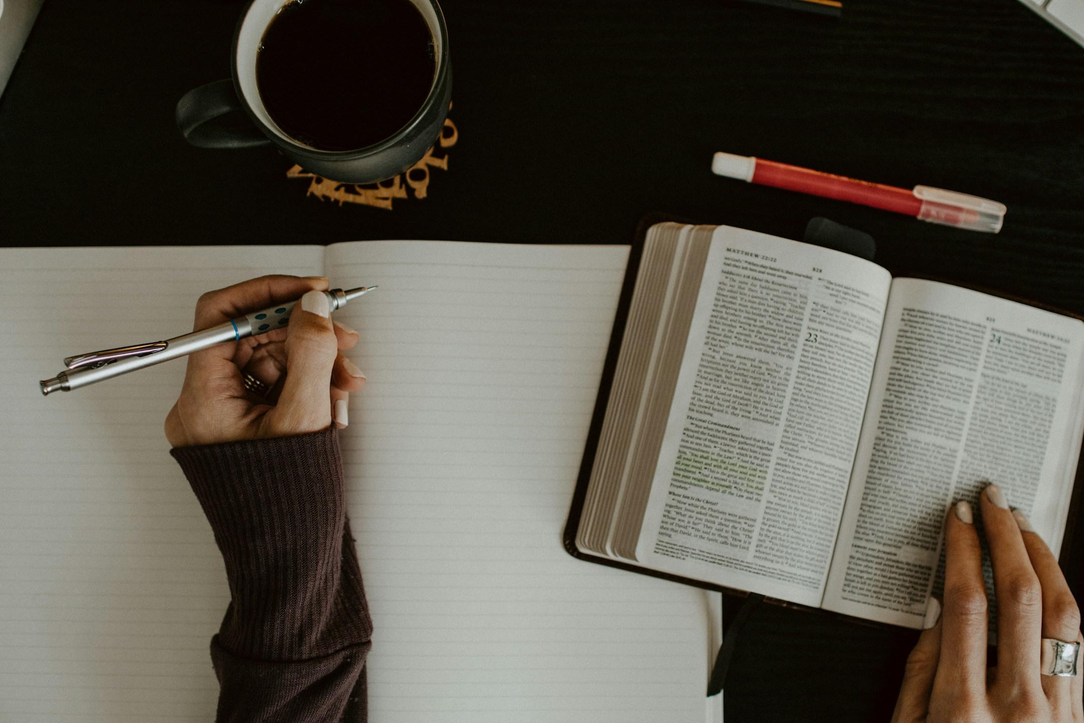 Woman's hands with Bible open and blank notebook