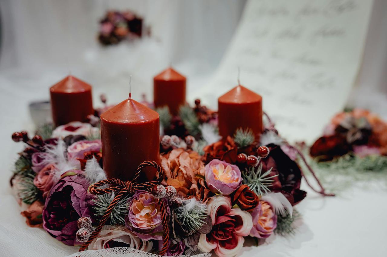Warm, festive candle wreath adorned with floral decorations, perfect for Christmas table settings.