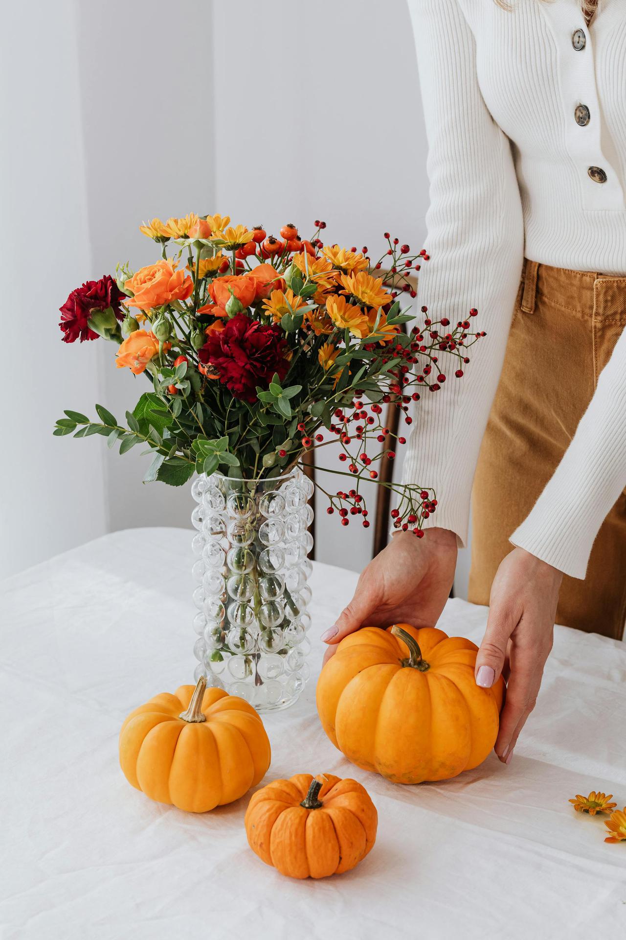 Colorful autumn floral arrangement and pumpkins on a table.